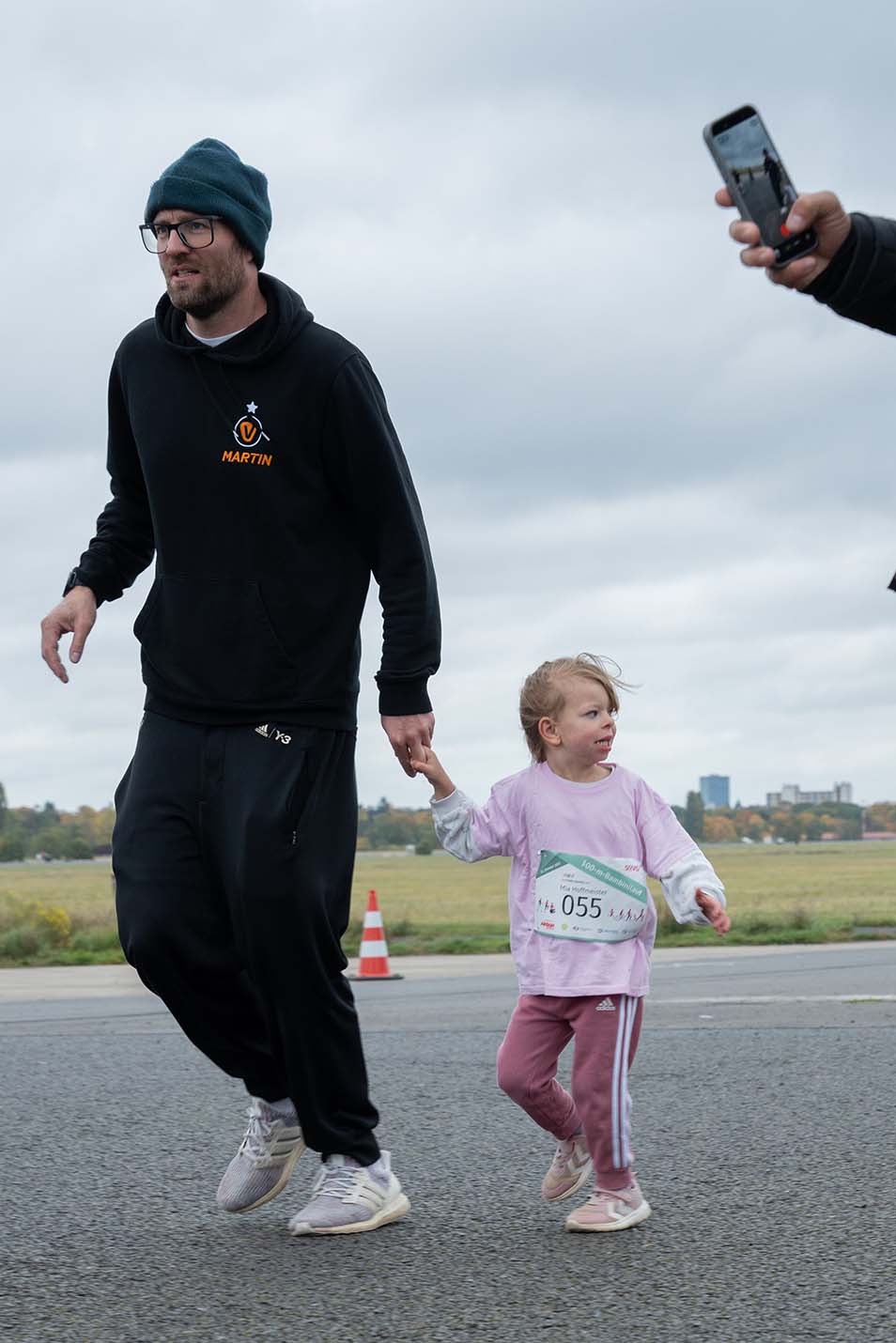 Ein Mann hält ein kleines Kind an der Hand.